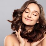 Brunette girl with healthy curly hair and natural make up . Beautiful model woman with wavy hairstyle .Care and beauty